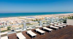 balkon z białymi krzesłami i plażą w obiekcie Waldorf Suite Hotel w Rimini