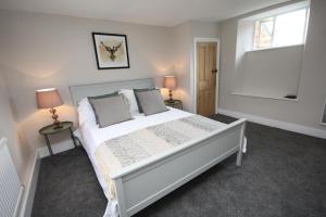 um quarto com uma grande cama branca e 2 candeeiros em Malvern House em Banbury