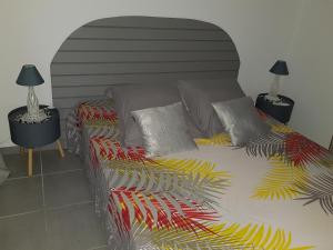 a bed with a colorful comforter and two lamps at Maison Laurencia - Appartement de l'étage in Sainte-Anne