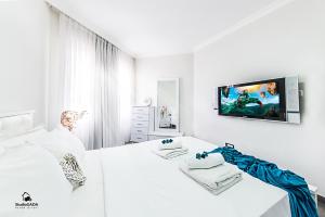 a white bedroom with a tv on the wall at Turists Vacation Sea of Galilee in Tiberias