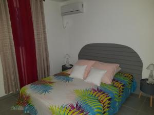1 dormitorio con 1 cama con sábanas y almohadas coloridas en Maison Laurencia - Appartement de l'étage, en Sainte-Anne