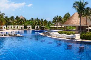 uma piscina num resort com cadeiras e guarda-sóis em Catalonia Playa Maroma - All Inclusive em Playa del Carmen