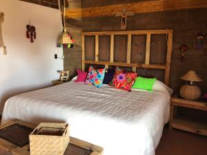 - une chambre avec un grand lit et des oreillers colorés dans l'établissement Zoyatl - Xamikal, à Zacatlán