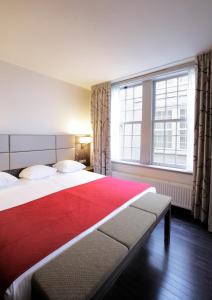 a bedroom with two beds and a large window at Krasnapolsky Apartments in Amsterdam