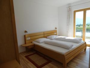 a bed in a room with a large window at Fasslhof in Cornaiano