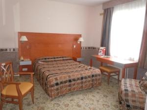 una camera d'albergo con letto, tavolo e sedie di Hôtel Le Bellevue Montrichard 3 étoiles a Montrichard