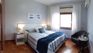 um quarto com uma cama, uma cadeira e uma janela em ATLÂNTIDA 210 , Xangri-lá RS em Xangri-lá