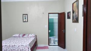 ein Schlafzimmer mit einem Bett und einer Tür zu einem Bad in der Unterkunft Chalés Porto do Céu in Aracati