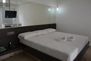 ein weißes Bett mit zwei weißen Kissen und einem Spiegel in der Unterkunft Ele e Ela Motel (Adult Only) in São Gonçalo do Amarante