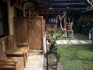 a patio with a chair and flowers in a yard at Rumah Daun Homestay Tetebatu in Tetebatu