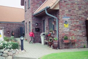 Eine Frau, die vor einem Backsteingebäude steht. in der Unterkunft Ferienhaus Wattenhus in Büsum