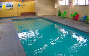 a large swimming pool with colorful chairs in a building at Toora Tourist Park in Toora