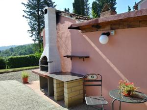 una casa rosa con patio y horno al aire libre. en Podere Il Leccione, en Palaia
