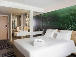 a bedroom with a large white bed and a bathroom at Novotel Paris Charles de Gaulle Airport in Roissy-en-France
