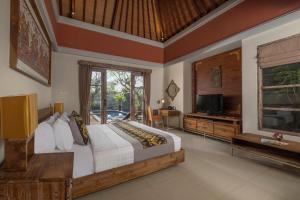 a bedroom with a large bed and a television in it at The Wolas Villas in Seminyak