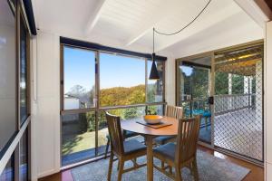 a dining room with a table and chairs and large windows at Ravensbourne Escape - Windsong in Ravensbourne