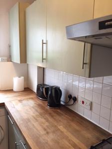 a kitchen with a wooden counter top and white tiles at Perfect 2 Bedroom Flat Shepherds Bush W12 in London