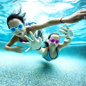 Dos chicas están nadando en una piscina en CampWest, en Oksbøl