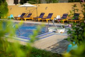 a swimming pool with lounge chairs and an umbrella at The Giggling Tree in Yangshuo