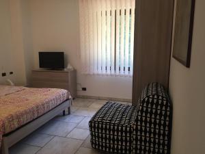 a bedroom with a bed and a chair and a window at Villa Althea in Ronago