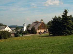 a field of green grass with a church and a house at Ferienwohnung Am Kanadablick in Stützengrün