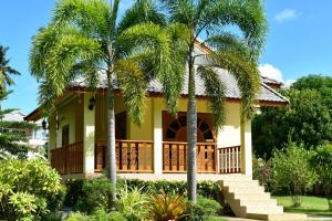 a house with palm trees in front of it at Kate House Bangsaphan in Bang Saphan