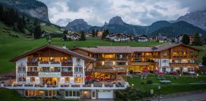um hotel numa aldeia com montanhas ao fundo em Hotel Welponer em Selva di Val Gardena