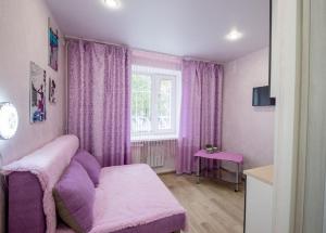 ブラゴヴェシチェンスクにあるSweet Homeの紫色のベッドと窓が備わる客室です。