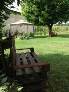 a wooden bench sitting in the grass with an umbrella at Poderi Sartoris in San Marzano Oliveto
