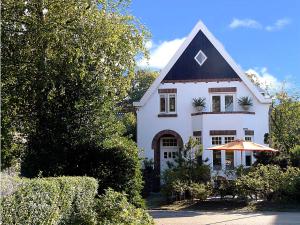Casa blanca con techo negro y sombrilla en Ons Buiten, en Bergen