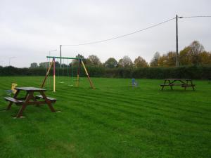 two picnic tables and a swing set in a field at Chambres d'Hôtes Mazurier in Cozes