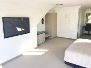 a bedroom with a bed and a flat screen tv at Avalon Manor Motel in Motueka