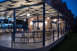 a patio with tables and chairs on a balcony at night at Akroyiali Resort in Vasiliki