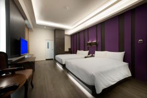una camera d'albergo con due letti e una parete viola di Two Fukun Hotel a Jiaoxi