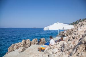 two people sitting on a beach under an umbrella at Sunset Villa Hotel in Kaş