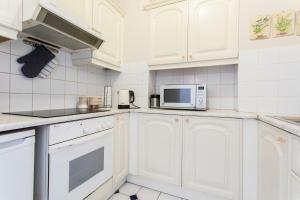 a white kitchen with white cabinets and a microwave at St Patricks Cathedral Self Catering in Dublin