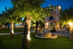 a park with trees and a bench in front of a building at Akroyiali Resort in Vasiliki
