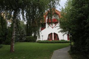 a building with a red and white facade with a green yard at Grantek Üdülőház in Balatonlelle