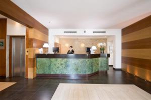 Ein Mann steht an einem Empfangstresen in der Lobby eines Hotels. in der Unterkunft Quality Hotel Nova Domus in Rom