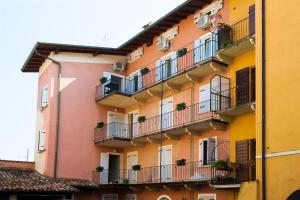 a pink and yellow building with potted plants on balconies at Garda Friends Apartments in Toscolano Maderno
