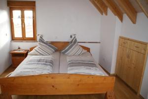 1 dormitorio con 1 cama de madera y 2 almohadas en Gästehaus Ehrhardt, en Schweigen-Rechtenbach