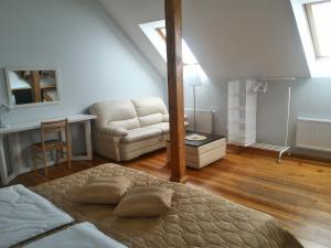 um quarto com uma cama, um sofá e uma cadeira em Miško Apartments em Silutė