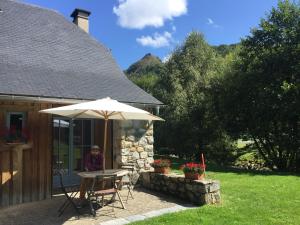una mujer sentada en una mesa bajo una sombrilla en Les chalets d'Arrens, en Arrens-Marsous