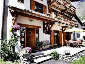 a building with a balcony and a table and chairs at Chez Mamie Anna (B&B et Chalet) in Bessans