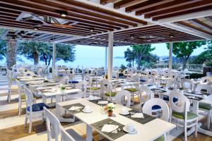 a restaurant with white tables and white chairs at Alexandra Beach Spa Resort in Potos