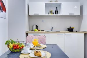 a kitchen with a table with food and a bowl of fruit at D&A Amphitheatre Apartments with free parking in Pula