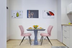a table with two pink chairs and a table with food on it at D&A Amphitheatre Apartments with free parking in Pula