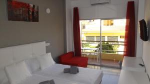 a bedroom with a bed and a red chair and a window at Hotel Carlos I in Torremolinos