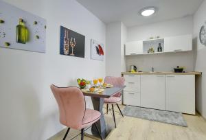 a kitchen with a table and two pink chairs at D&A Amphitheatre Apartments with free parking in Pula