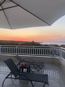 a balcony with two chairs and a table with a sunset at Apartments Malina in Vir